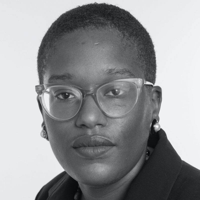 Black and white headshot of Terri Henderson, a young black woman with very short hair wearing glasses and small earrings, looking straight forward with a serious expression.