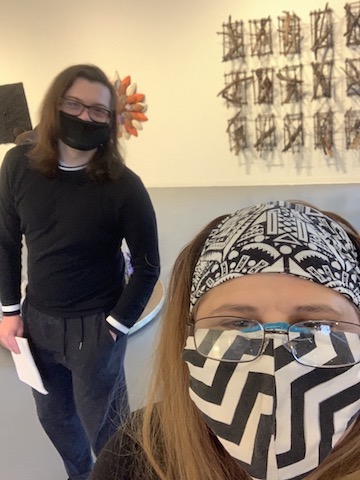 Sandra Abbott (lower right) and Pierce Johnson (left) vist the Creative Alliance at the Patterson in Baltimore City. The gallery in the background displays artworks hung on white walls.